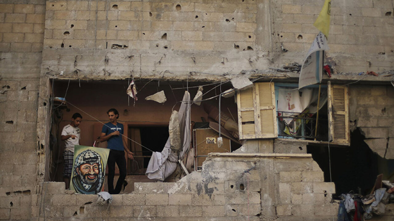 Palestinians stand next to a picture depicting late Palestinian leader Arafat as they inspect a house which police said was damaged in an Israeli air strike in Gaza City Palestinians stand next to a picture depicting late Palestinian leader Yasser Arafat as they inspect a house which police said was damaged in an Israeli air strike in Gaza City July 10, 2014. Israeli air strikes killed eight members of a family including five children in a pre-dawn raid on Gaza on Thursday, Palestinian officials said, while Hamas-led fighters launched rockets at Tel Aviv and other Israeli cities. REUTERS/Mohammed Salem (GAZA - Tags: POLITICS CIVIL UNREST TPX IMAGES OF THE DAY) - RTR3X