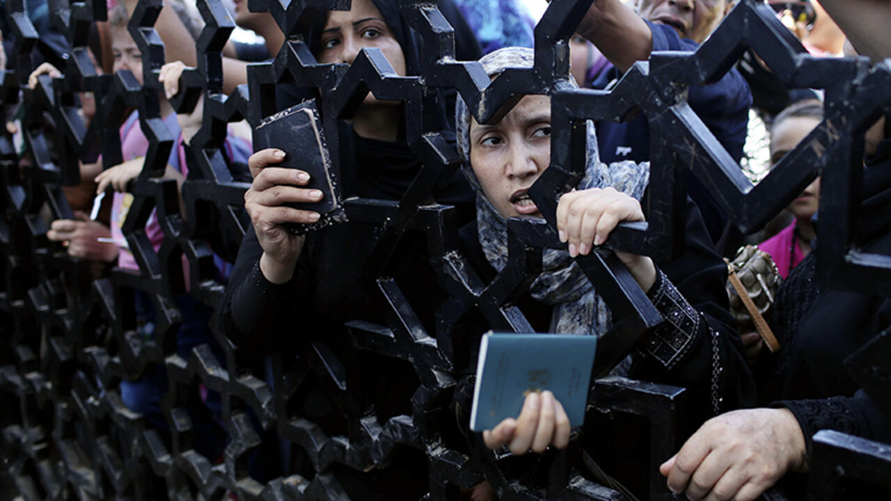 Palestinians standing behind the gate of Rafah crossing hold their passports as they try to cross into Egypt, in the southern Gaza Strip Palestinians standing behind the gate of Rafah crossing hold their passports as they try to cross into Egypt, in the southern Gaza Strip July 10, 2014. At least 74 Palestinians, most of them civilians, have been killed in Israel's Gaza offensive, Palestinian officials said on Thursday, and militants kept up rocket attacks on Tel Aviv and other cities in warfare showing no signs of ending soon. Egypt's state news agency said Egyptian authorities had decided to open the Rafah border crossing to Gaza on Thursd