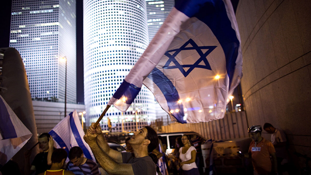 A right wing activist waves a flag during a protest in support of Israel's offensive in the Gaza Strip, in Tel Aviv. A right wing activist waves a flag during a protest in support of Israel's offensive in the Gaza Strip, in Tel Aviv July 29, 2014. An Israeli television station retracted its report on Tuesday that a ceasefire in the Gaza conflict had been agreed, saying instead there was "movement" toward a truce between Israel and the Palestinian territory's dominant Hamas Islamists being brokered by Egypt. REUTERS/Ronen Zvulun (ISRAEL - Tags: POLITICS CIVIL UNREST) - RTR40KAT