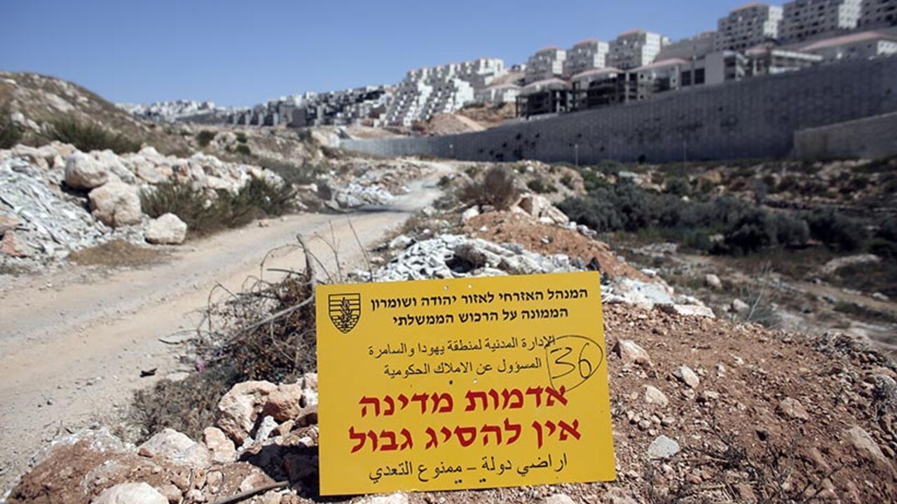 ISRAEL-PALESTINIAN-CONFLICT-SETTLEMENTS An official Israeli sign from the Civil Administration in Charge of the Government Property, placed in the West Bank near the Israeli Beitar Illit (R) settlement, states that the area is state land and trespassing is not allowed, near the Palestinian village of Wadi Fukin, on September 4, 2014. Israel over the weekend said it would expropriate 400 hectares (988 acres) of Palestinian land around Bethlehem, and allowed 45 days for any appeal. AFP PHOTO / AHMAD GHARABLI (Photo credit should read AHMAD G