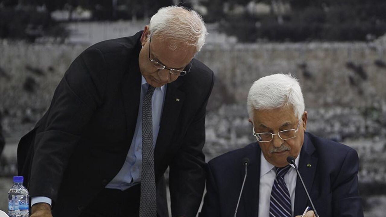 Palestinian chief negotiator Saeb Erekat helps Palestinian President Mahmoud Abbas as he signs international conventions during a meeting with Palestinian leadership in Ramallah Palestinian chief negotiator Saeb Erekat (L) helps Palestinian President Mahmoud Abbas as he signs international conventions during a meeting with Palestinian leadership in the West Bank City of Ramallah April 1, 2014. Abbas signed more than a dozen international conventions on Tuesday citing anger at Israel's delay of a prisoner release, in a move jeopardised U.S. efforts to salvage fragile peace talks. REUTERS/Mohamad Torokman (WEST BANK - Tags: POLITICS) - RTR3JIOF