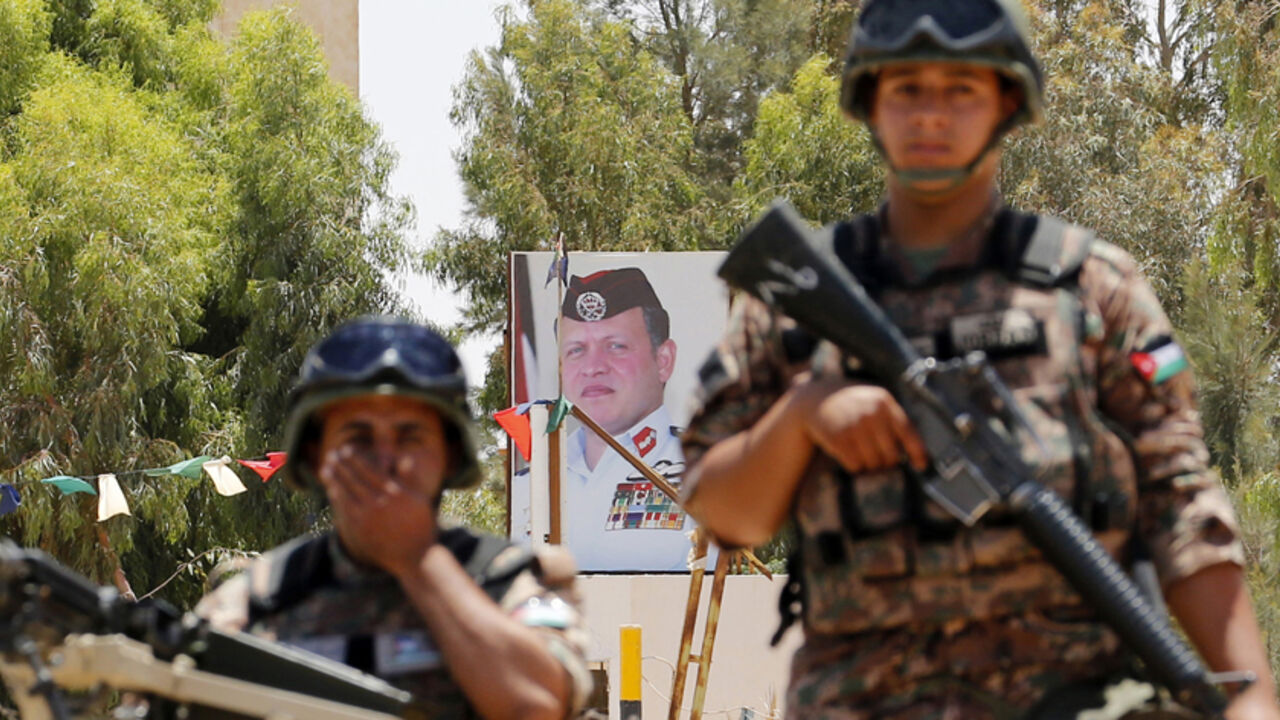 Jordanian soldiers stand guard in front of a poster for Jordan's King Abdullah near the Jordanian Karameh border crossing Jordanian soldiers stand guard in front of a poster for Jordan's King Abdullah near the Jordanian Karameh border crossing on the Jordanian-Iraqi border, near Ruweished city June 25, 2014. REUTERS/Muhammad Hamed (JORDAN - Tags: POLITICS CIVIL UNREST MILITARY ROYALS) - RTR3VOW9