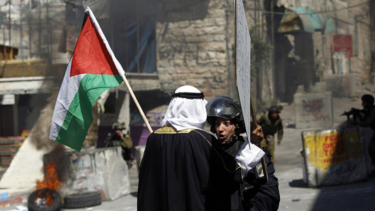 Palestinian man holding a Palestinian national flag argues with an Israeli policewoman, during a protest against the Israeli offensive in Gaza, in the West Bank city of Hebron A Palestinian man holding a Palestinian national flag argues with an Israeli policewoman, during a protest against the Israeli offensive in Gaza, in the West Bank city of Hebron August 22, 2014. REUTERS/Mohamad Torokman (WEST BANK - Tags: POLITICS CIVIL UNREST CONFLICT TPX IMAGES OF THE DAY) - RTR43D91