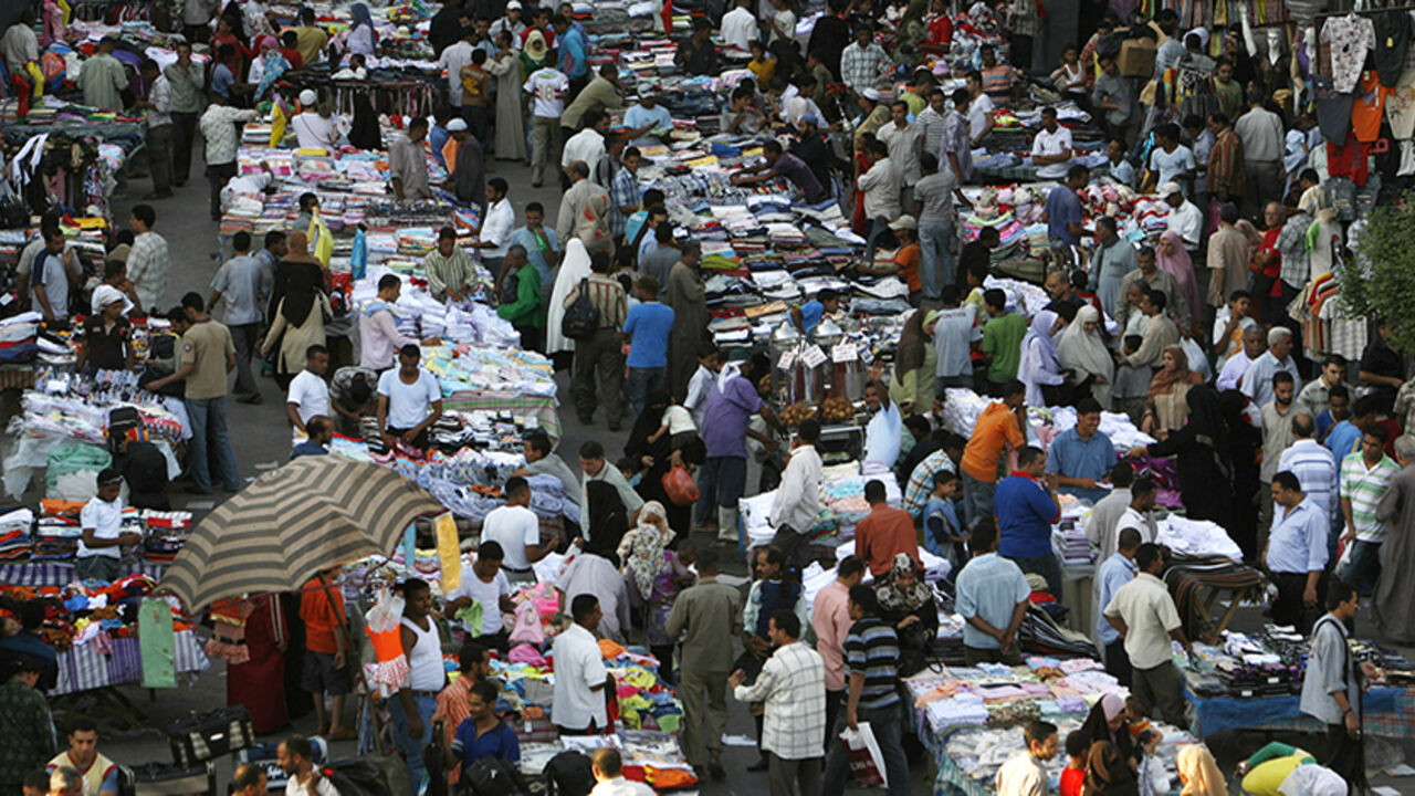 To match feature EGYPT-POPULATION/ Egyptian citizens walk on a main street in central Cairo June 20, 2008. Red and white banners along Nile bridges and Cairo streets this month were Egypt's latest effort to curb an increasingly pressing problem: a population growing faster than the economy can support. To match feature EGYPT-POPULATION/ REUTERS/Asmaa Waguih (EGYPT) - RTX7JKV