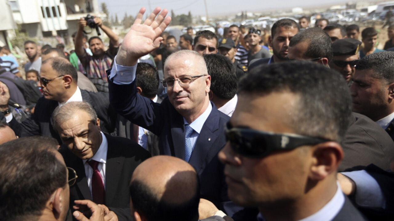 Palestinian PM Hamdallah waves as he visits houses that witnesses said were destroyed during the recent seven-week Israeli offensive, in the Shejaia neighbourhood, east of Gaza City Palestinian Prime Minister Rami Hamdallah (C) waves as he visits houses that witnesses said were destroyed during the recent seven-week Israeli offensive, in the Shejaia neighbourhood, east of Gaza City October 9, 2014. Technocrat Hamdallah arrived in the Hamas-dominated Gaza Strip on Thursday to convene the first meeting of a unity government there since a brief civil war in 2007 between Hamas and forces loyal to the Fatah party. REUTERS/Ibraheem Abu Mustafa (GAZA - Tags: POLITICS CIVIL UNREST TPX IMAGES O