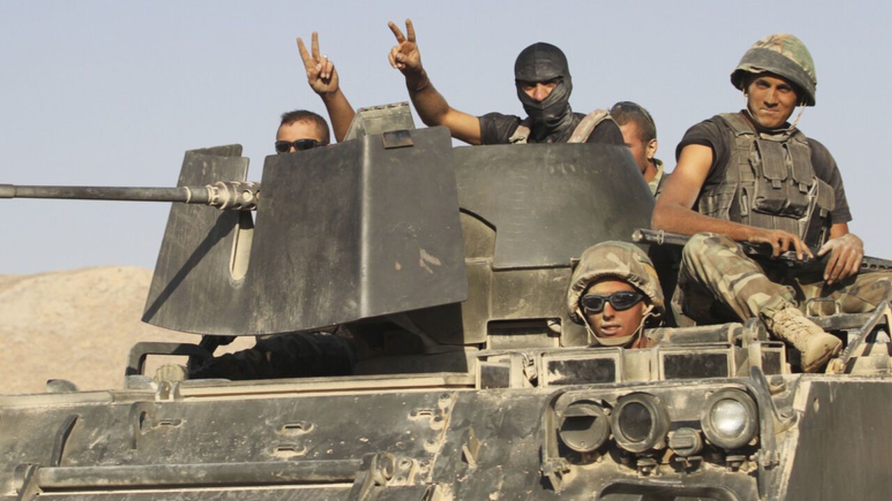 Lebanese army soldiers gesture while riding on an armoured vehicle as they exit the Sunni Muslim border town of Arsal, in eastern Bekaa Valley August 28, 2014. Gunmen killed at least one Lebanese soldier on Thursday when they attacked an army post at the border with Syria on Thursday near a town seized by Islamist insurgents earlier this month, a security source said. Three soldiers were wounded in the clash in the mountainous border zone just outside the town of Arsal, which was held for five days by milit