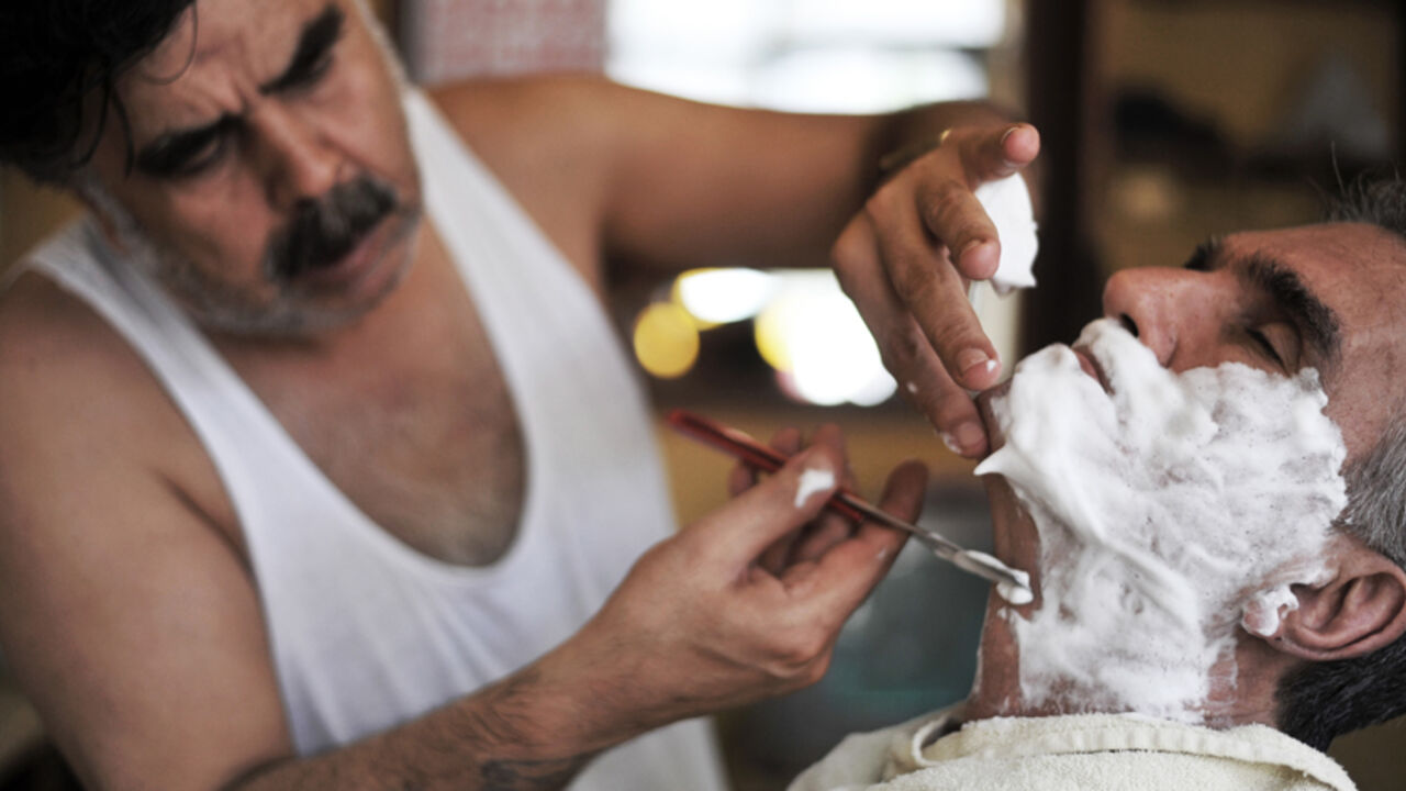 CORRECTION-TURKEY-THEME-HAIR TO GO WITH STORY BY PHILIPPE ALFROY
A Turkish barber Mehmet Haskan shaves a client at his salon at Tarlabasi on July 19, 2013 in Istanbul. AFP PHOTO/OZAN KOSE (Photo credit should read OZAN KOSE/AFP/Getty Images)