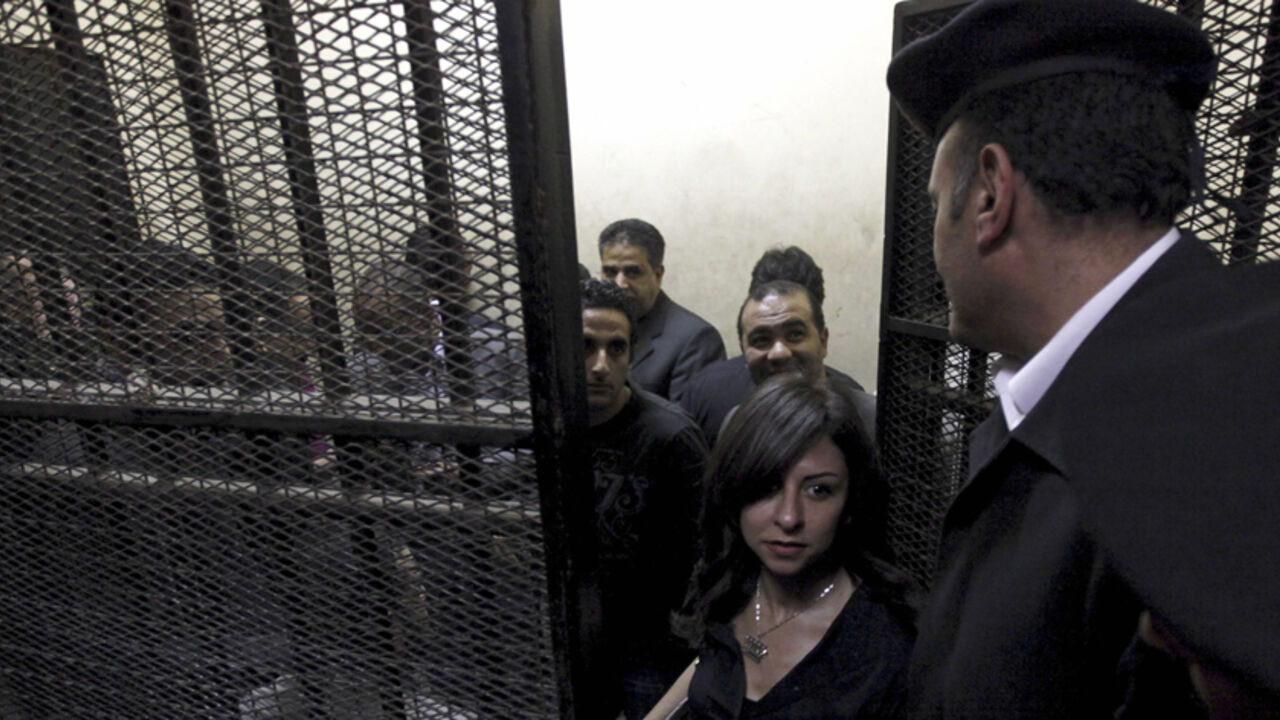 Activists, accused of working for unlicensed non-governmental organizations (NGOs) and receiving illegal foreign funds, stand in a cage during the opening of their trial in Cairo March 8, 2012. An Egyptian judge said on Thursday he was delaying until April 10 the trial of civil society activists including 16 Americans accused of receiving illegal foreign funds and pursuing their pro-democracy activities without a licence. REUTERS/Mohamed Abd El Ghany  (EGYPT - Tags: CIVIL UNREST POLITICS CRIME LAW) - RTR2Z1