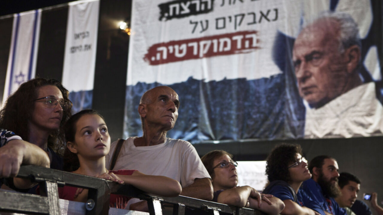 Israelis take part in a mass rally marking the 17th anniversary of the assassination of former Israeli prime minister Yitzhak Rabin, in Tel Aviv Israelis take part in a mass rally marking the 17th anniversary of the assassination of former Israeli prime minister Yitzhak Rabin, in Tel Aviv October 27, 2012. Israel on Saturday marked the 17th anniversary of Rabin's assassination by an ultra-nationalist Jew. The words in Hebrew near Rabin's photo read "Remembering the murder, fighting for democracy". REUTERS/ Nir Elias (ISRAEL - Tags: POLITICS ANNIVERSARY) - RTR39NVH