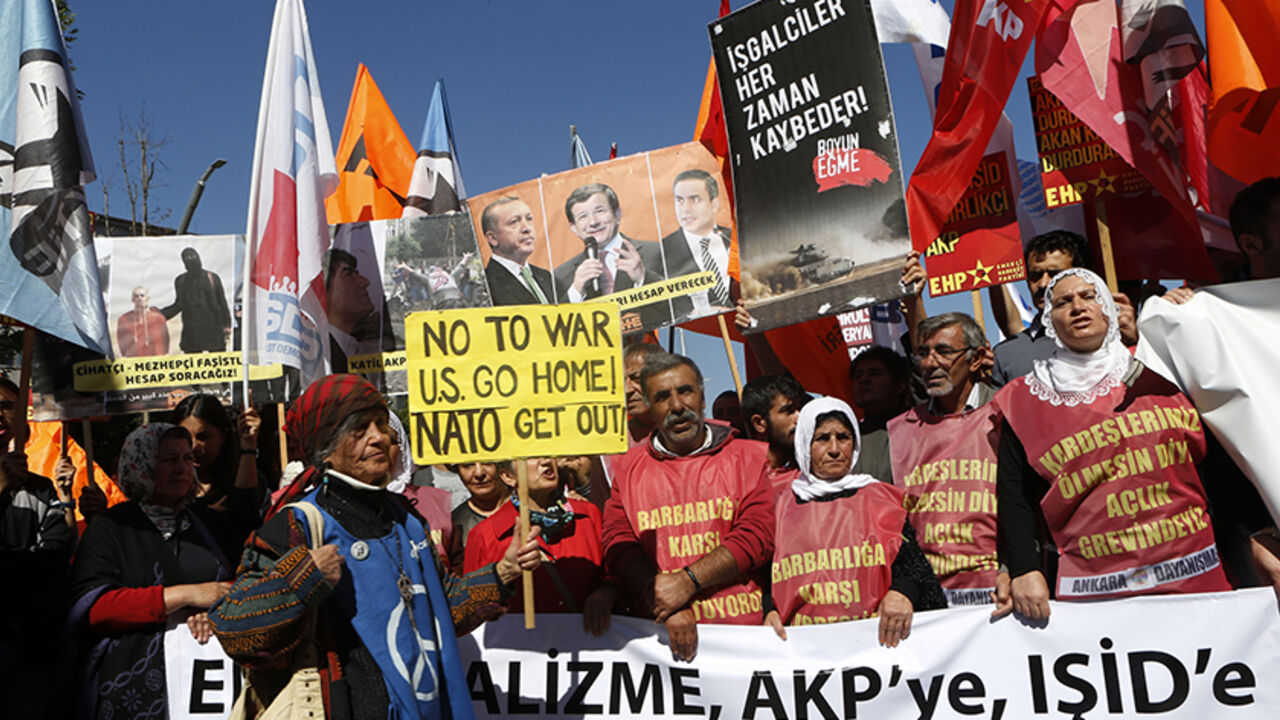 Protesters demonstrate in front of the Turkish Parliament in Ankara Protesters demonstrate in front of the Turkish Parliament in Ankara October 2, 2014. The protest was held hours before a debate for MPs to vote on a motion, which would allow the government to authorise cross-border military incursions against Islamic State fighters in Syria and Iraq, and allow coalition forces to use Turkish territory. The placard (in black) reads, "Occupiers always lose." The shirts read (from L-R), "We are demonstrating against barbarism" and "We are on a hunger strike for the safety of