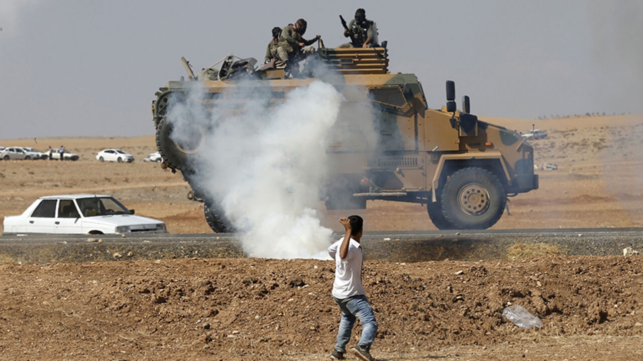 A protester throws stones at an armoured army vehicle during a pro-Kurdish demonstration, near the Mursitpinar border crossing on the Turkish-Syrian border, in Suruc A protester throws stones at an armoured army vehicle during a pro-Kurdish demonstration in solidarity with people of Kobani, near the Mursitpinar border crossing on the Turkish-Syrian border, in the Turkish town of Suruc in southeastern Sanliurfa province October 7, 2014. Islamic State fighters advanced into the south west of the Syrian Kurdish town of Kobani overnight, a monitoring group said on Tuesday, taking several buildings to gain attacking positions from two sides of the city. REUTERS/Umit Bektas