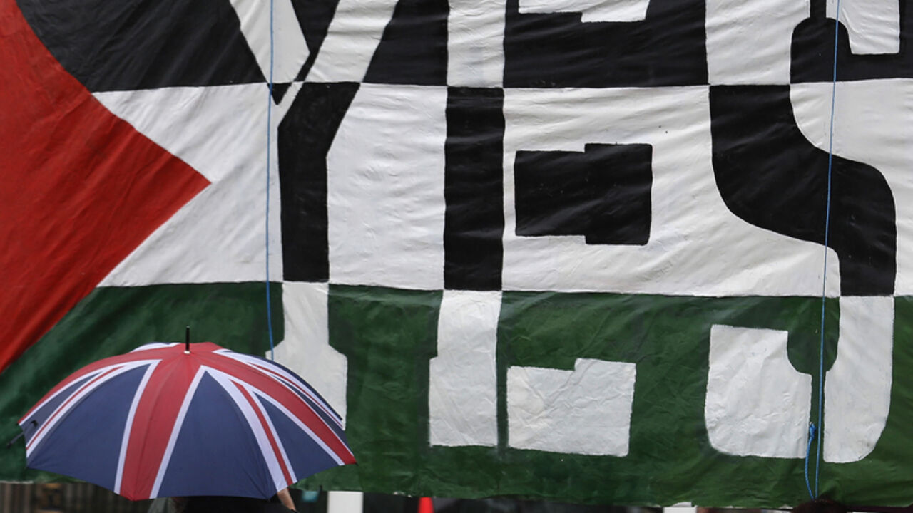 A passer-by carries a Union Flag umbrella past a pro-Palestine demonstration outside the Houses of Parliament in London A passer-by carries a Union Flag umbrella past a pro-Palestine demonstration outside the Houses of Parliament in London October 13, 2014. British Prime Minister David Cameron will not take part in a parliamentary vote on whether the government should recognise Palestine as a state, his spokesman said on Monday ahead of a debate designed to raise the political profile of the issue. REUTERS/Luke MacGregor (BRITAIN - Tags: POLITICS) - RTR4A005