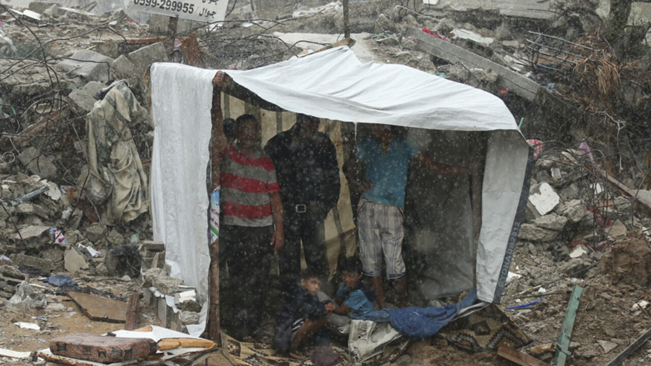 MIDEAST-GAZA/ Palestinians take cover from rain inside a makeshift shelter near the ruins of their houses, that witnesses said were destroyed during a seven-week Israeli offensive, in the east of Gaza City October 19, 2014. An open-ended ceasefire between Israel and Hamas-led Gaza militants, mediated by Egypt, took effect on August 26 after a seven-week conflict. It called for an indefinite halt to hostilities, the immediate opening of Gaza's blockaded crossings with Israel and Egypt, and a widening of the territory's f