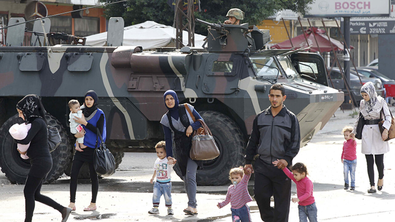 Civilians walk past a Lebanese army soldier patrolling on an armoured vehicles following clashes between Lebanese soldiers and Islamist gunmen in Tripoli Civilians walk past a Lebanese army soldier patrolling on an armoured vehicles after being deployed to tighten security following clashes between Lebanese soldiers and Islamist gunmen in Tripoli, northern Lebanon, October 27, 2014. Guns fell silent in the northern Lebanese city of Tripoli on Monday after two days of deadly battles between the army and Islamist gunmen, some of the worst fighting to spill over into Lebanon from Syria's civil war next door. REUTERS/Mohamed Azakir (LEBANON - Tags: POLITICS CIVI
