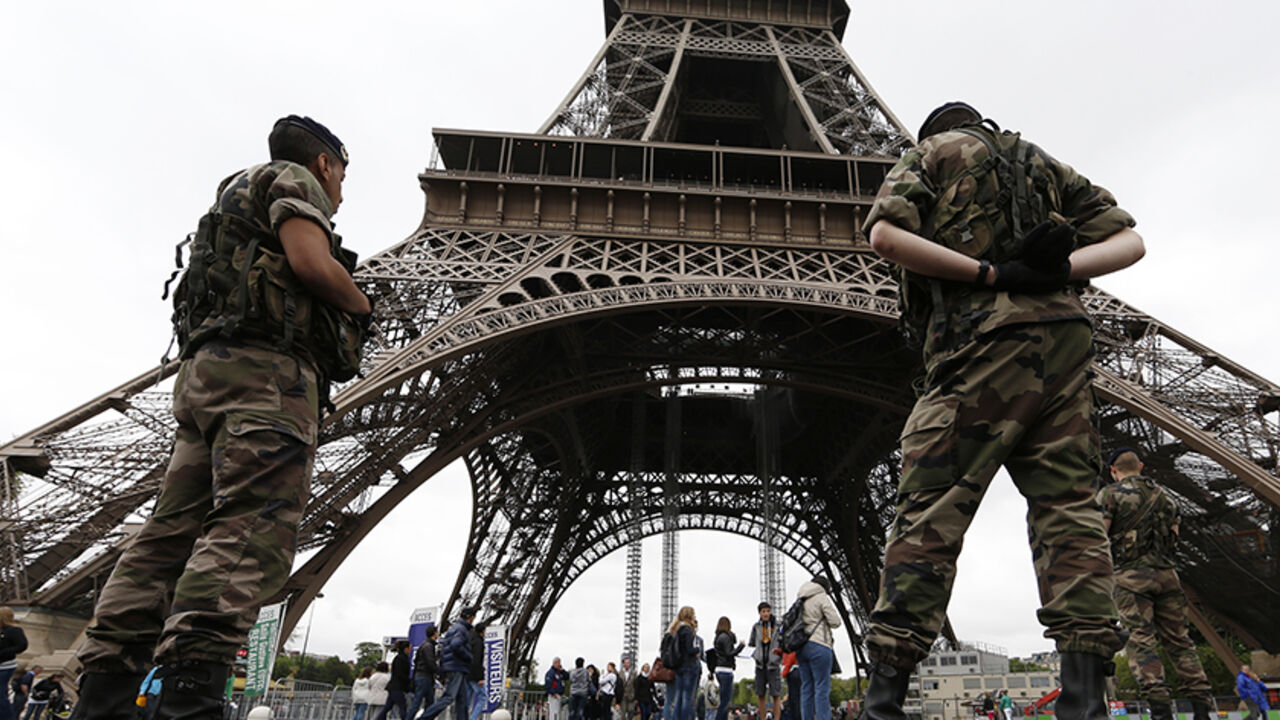 Soldiers stand by tourists as they patrol near the Eiffel Tower in Paris Soldiers stand by tourists as they patrol near the Eiffel Tower in Paris, May 8, 2013. President Francois Hollande said on Tuesday, May 7, that France was taking the threat from al Qaeda in the Islamic Maghreb (AQIM) seriously after a purported leader of the Islamist group called for attacks on French interests throughout the world. REUTERS/Gonzalo Fuentes (FRANCE - Tags: TRAVEL CIVIL UNREST MILITARY POLITICS) - RTXZEPE