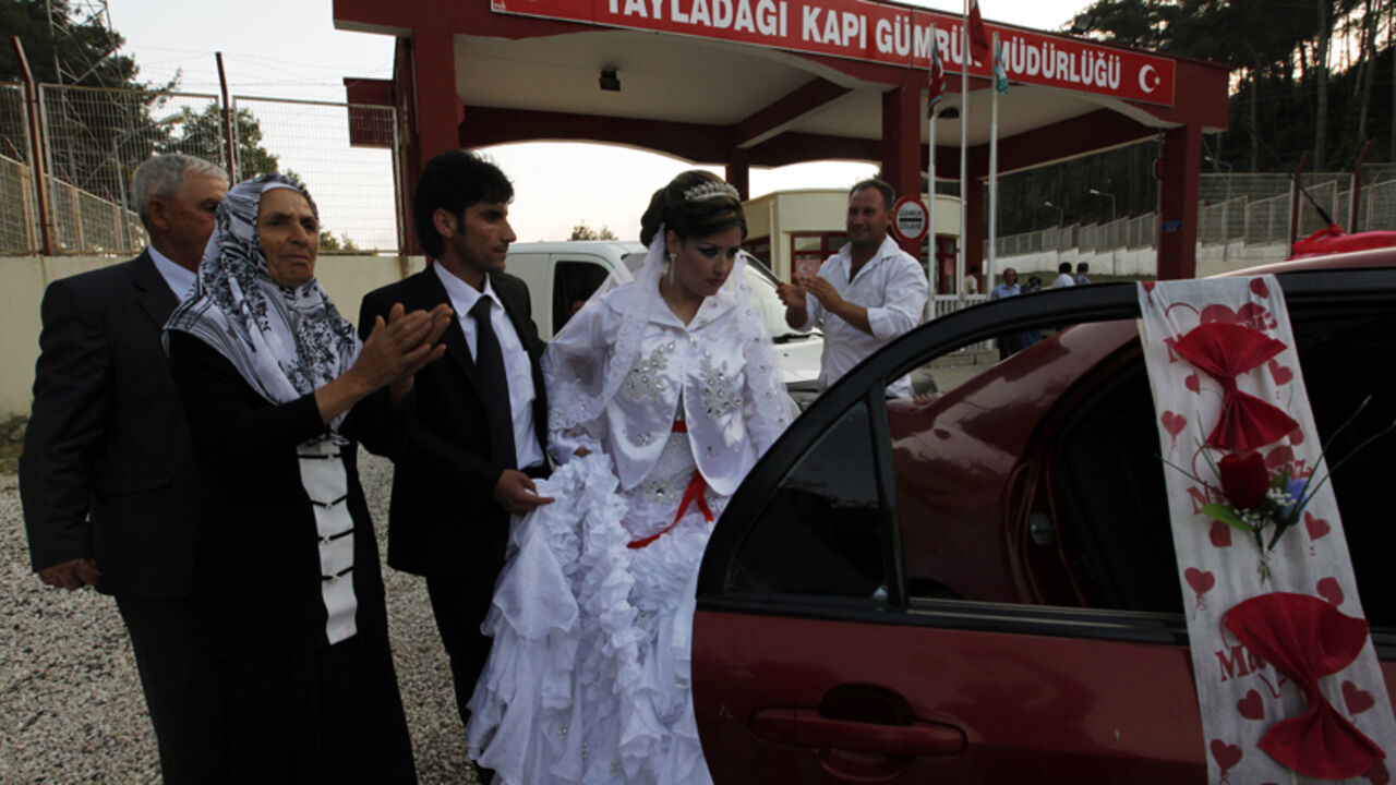 A Syrian bride and her Turkish groom leave the Turkish side of the Yayladagi border gate between Turkey and Syria in Hatay province for their wedding Syrian bride Reme and her Turkish groom Rasim Yuce leave the Turkish side of the Yayladagi border gate between Turkey and Syria in Hatay province for their wedding, after Reme's arrival from Syria, June 25, 2011. Reme, a 22-year-old hairdresser from Burj Islam, a Syrian village in Latakia province, has to cross the border for her wedding ceremony with 26-year-old driver Rasim Yuce from Aslanyazi, a Turkish village in Hatay Province. The couple met and fell in love during one of Yuce's business trips to Syri