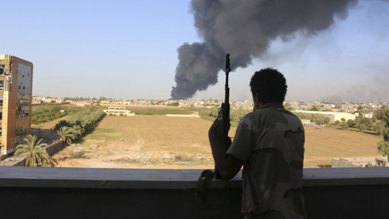 LIBYA-SECURITY/ A fighter from Zintan brigade watches as smoke rises after rockets fired by one of Libya's militias struck and ignited a fuel tank in Tripoli August 2, 2014. On Saturday, sporadic shelling resumed in the capital after two days of relative calm. Plumes of black smoke rose over the south of Tripoli from a burning fuel tank at the airport's fuel depot. REUTERS/Hani Amara (LIBYA - Tags: POLITICS CIVIL UNREST) - RTR411E4
