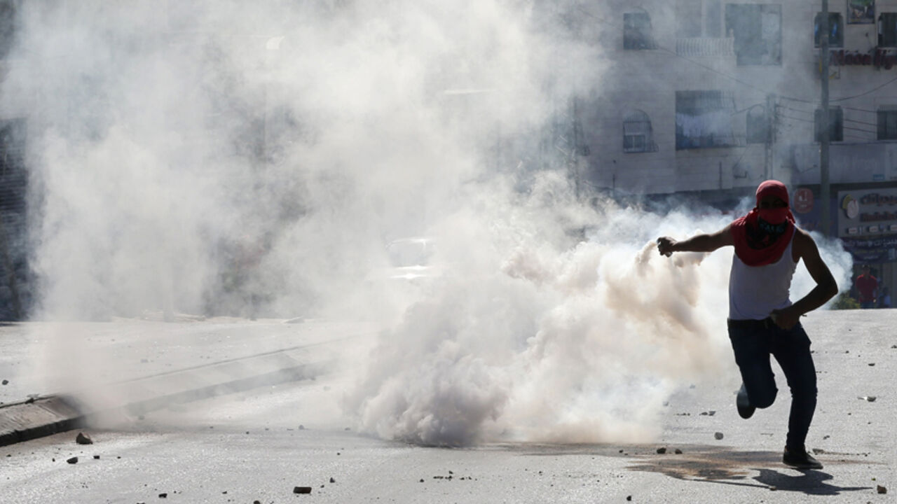 A Palestinian prepares to throw a tear gas canister fired by Israeli troops back to the soldiers during clashes in the West Bank city of Hebron A Palestinian prepares to throw a tear gas canister fired by Israeli troops back to the soldiers during clashes following a gun battle where the troops shot dead two Palestinians, Marwan Kawasme and Amar Abu Aysha, in the West Bank city of Hebron September 23, 2014. Israeli troops shot dead the two Palestinians in the West Bank city of Hebron on Tuesday and the military said they were members of Hamas responsible for the killing of three Israeli youths in June, an attack that led to the Gaza war. Kawasme an