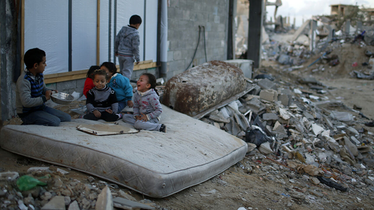 MIDEAST-GAZA/CONSTRUCTION Palestinian children play on a mattress near the ruins of houses which witnesses said were destroyed by Israeli shelling during the most recent conflict between Israel and Hamas, in the east of Gaza City December 1, 2014. According to housing minister Mufeed al-Hasayna, Gaza needs 8,000 tonnes of cement a day to meet demand. A new system set up with the United Nations to comply with Israeli requirements lets through at most 2,000, he said. At that rate, reconstruction would take more than 30 years, said Has