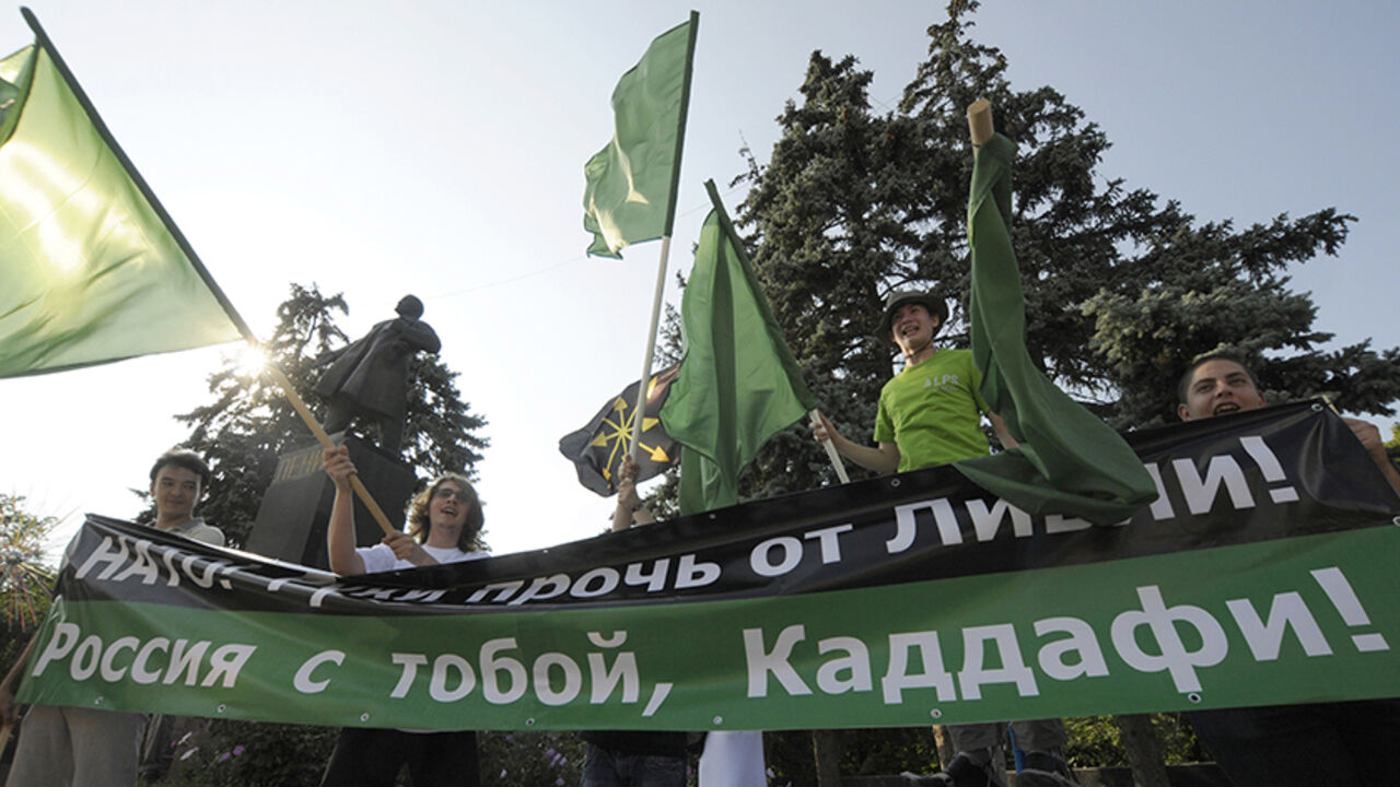 RUSSIA/ People take part in a rally to support Libya's leader Muammar Gaddafi and protest against the NATO military operation in Libya in the Russian city of Rostov-on-Don July 7, 2011. The banner reads "NATO: Hands off Libya! Russia is with you, Gaddafi". REUTERS/Sergei Karpov (RUSSIA - Tags: POLITICS CONFLICT CIVIL UNREST) - RTR2OKXP