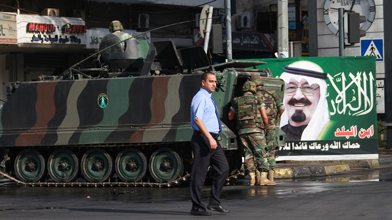 LEBANON-CRISIS/ A man walks past Lebanese Army soldiers patrolling a street in the Sunni Muslim Bab al-Tebbaneh neighbourhood, in Tripoli, northern Lebanon October 23, 2012. Four people were killed and 15 wounded in overnight gun battles in the Lebanese city of Tripoli in a second night of fighting between Sunni and Alawite gunmen loyal to different sides in the war in neighbouring Syria, a military source said on Tuesday. The poster in the background depicts Saudi Arabia's King Abdullah. REUTERS/Omar Ibrahim (LEBANON -