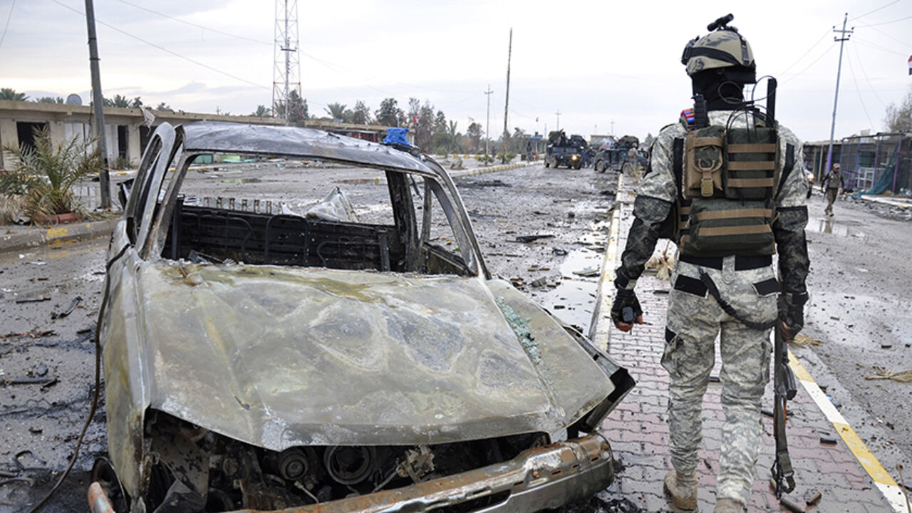 MIDEAST-CRISIS/ A member of the Iraqi security forces walks past a destroyed vehicle belonging to Islamic State militants during an intensive security deployment on the outskirts of Samarra December 14, 2014. Picture taken December 14, 2014. REUTERS/Stringer (IRAQ - Tags: CIVIL UNREST POLITICS MILITARY) - RTR4I0GG