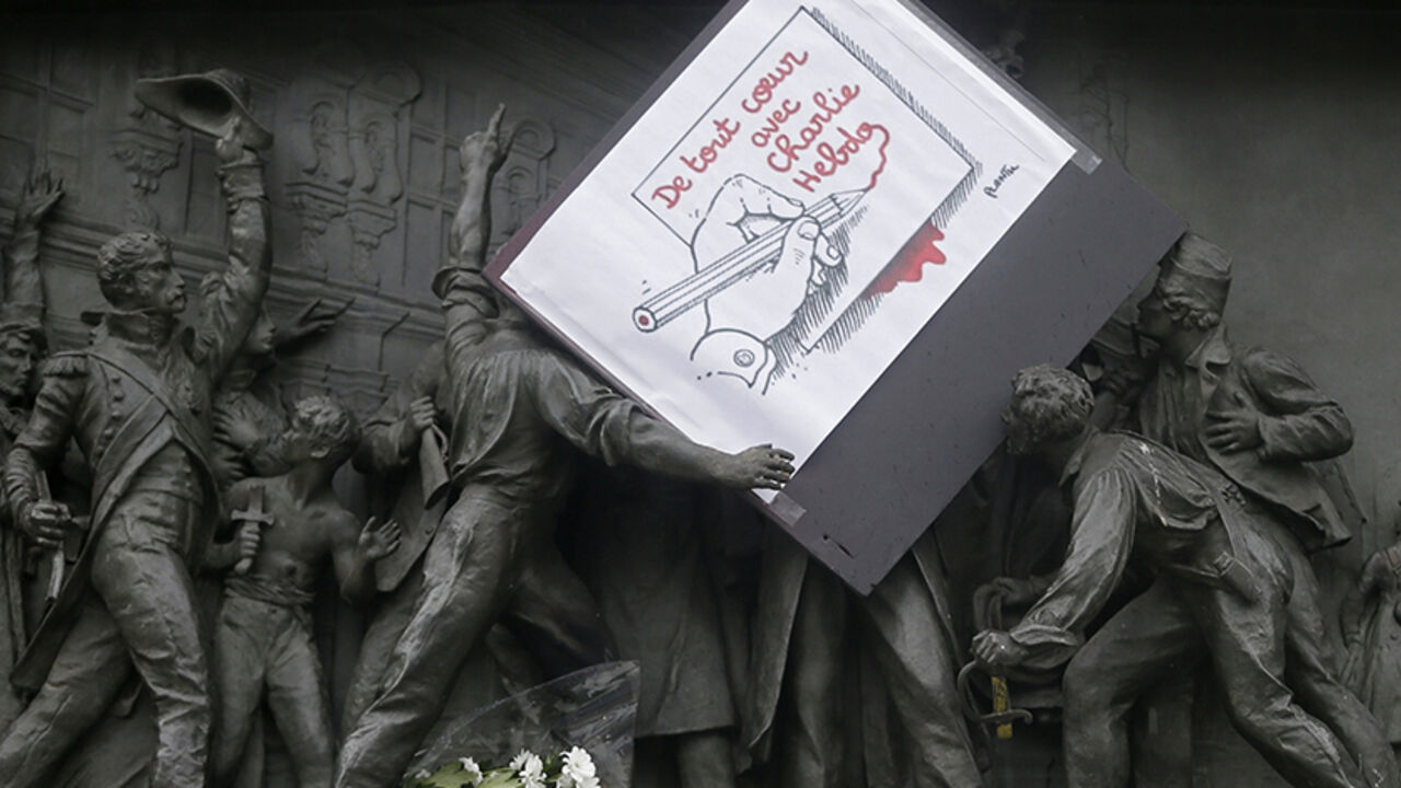 FRANCE-SHOOTING/ A placard with a press cartoon by cartoonist Plantu is placed amongst a frieze on the Republic statue at the Place de la Republique in Paris January 8, 2015 the day after a shooting at the Paris offices of weekly satirical newspaper Charlie Hebdo. French police extended a manhunt on Thursday for two brothers suspected of killing 12 people at a satirical magazine in Paris in a presumed Islamist militant strike that national leaders and allied states described as an assault on democracy. France began a day of