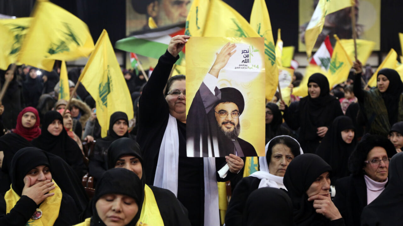Supporter of Lebanon's Hezbollah leader Nasrallah holds up a poster of him as he appears on a screen to speak at event to commemorate deaths of six Hezbollah fighters and Iranian general killed by Israeli air strike in Syria, in Beirut A supporter of Lebanon's Hezbollah leader Sayyed Hassan Nasrallah holds up a poster of him as he appears on a screen to speak at an event to commemorate the deaths of six Hezbollah fighters and an Iranian general killed by an Israeli air strike in Syria on January 18, in Beirut's southern suburbs, January 30, 2015. Nasrallah said on Friday his group did not want war with Israel but was ready for one and had the right to respond to Israeli "aggression" in any time and place. The words on the woman's hand rea