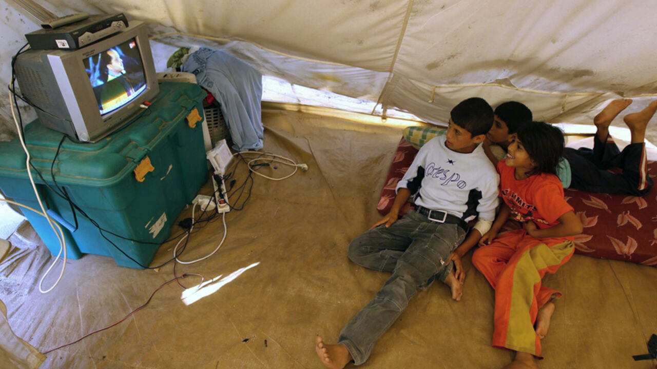 Palestinian children from the Al-Qarawi family watch television in a tent in the northern Gaza Strip June 9, 2010. The tent was erected after their family's house was destroyed during Israel's three-week offensive in Gaza last year. REUTERS/Mohammed Salem (GAZA - Tags: POLITICS CIVIL UNREST) - RTR2EY18