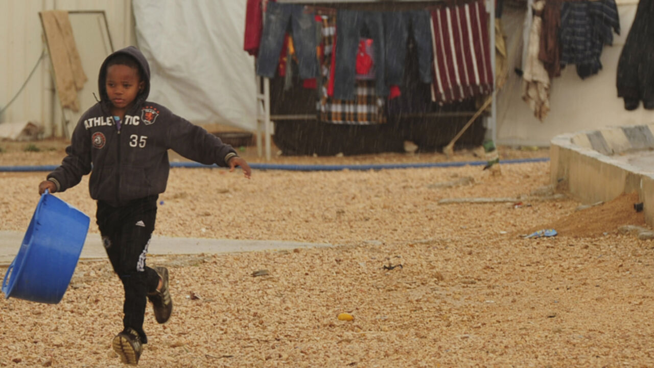 LIBYA/ A child from the town of Tawargha runs in the rain in a refugee camp in Benghazi January 11, 2012. The Tawargha residents, who are waiting to return to their town after reprisals from anti-Gaddafi loyalists after the revolution, say that conditions in the camp are harsh and that their children have not been able to go to school in the new year. REUTERS/Esam Al-Fetori (LIBYA - Tags: POLITICS CIVIL UNREST SOCIETY) - RTR2W5I6