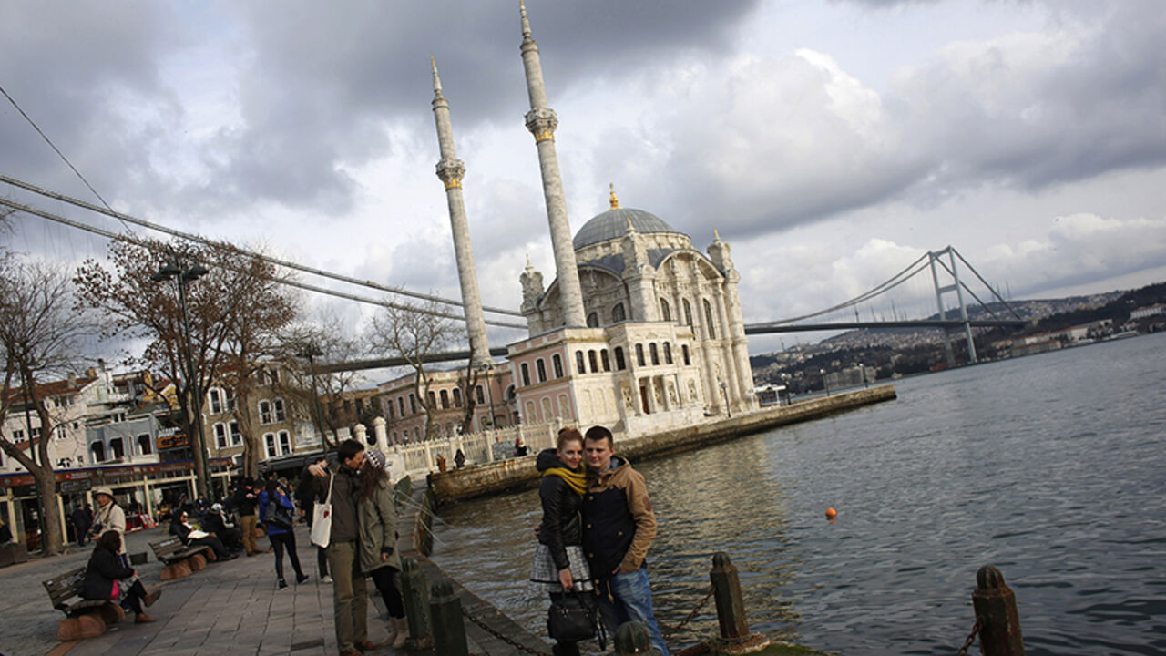 TURKEY-DAILYLIFE/ Couples pose for souvenir pictures in front of the Ottoman-era Ortakoy Mecidiye mosque by the Bosphorus strait in Istanbul January 5, 2015. REUTERS/Murad Sezer (TURKEY - Tags: RELIGION CITYSCAPE TRAVEL SOCIETY) - RTR4K534