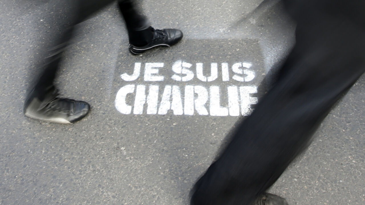 People walk past a grafitti tag reading "I am Charlie" as they take part in a solidarity march (Marche Republicaine) in the streets of Paris January 11, 2015. French citizens will be joined by dozens of foreign leaders, among them Arab and Muslim representatives, in a march on Sunday in an unprecedented tribute to this week's victims following the shootings by gunmen at the offices of the satirical weekly newspaper Charlie Hebdo, the killing of a police woman in Montrouge, and the hostage taking at a kosher