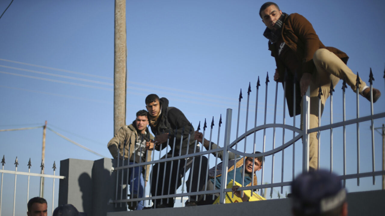 PALESTINIANS-EGYPT/CROSSING Palestinians, hoping to cross into Egypt, climb a wall as policemen loyal to Hamas stand guard at the Rafah crossing between Egypt and the southern Gaza Strip January 20, 2015. Egyptian authorities opened Rafah crossing, Gaza's main window to the outside world, on Tuesday for three days, officials said. Egypt shut the crossing over violence with Islamist militants in Egypt's adjacent Sinai region last October. Since then, it opened the crossing partially and on a few occasions to allow thousands of Palestin