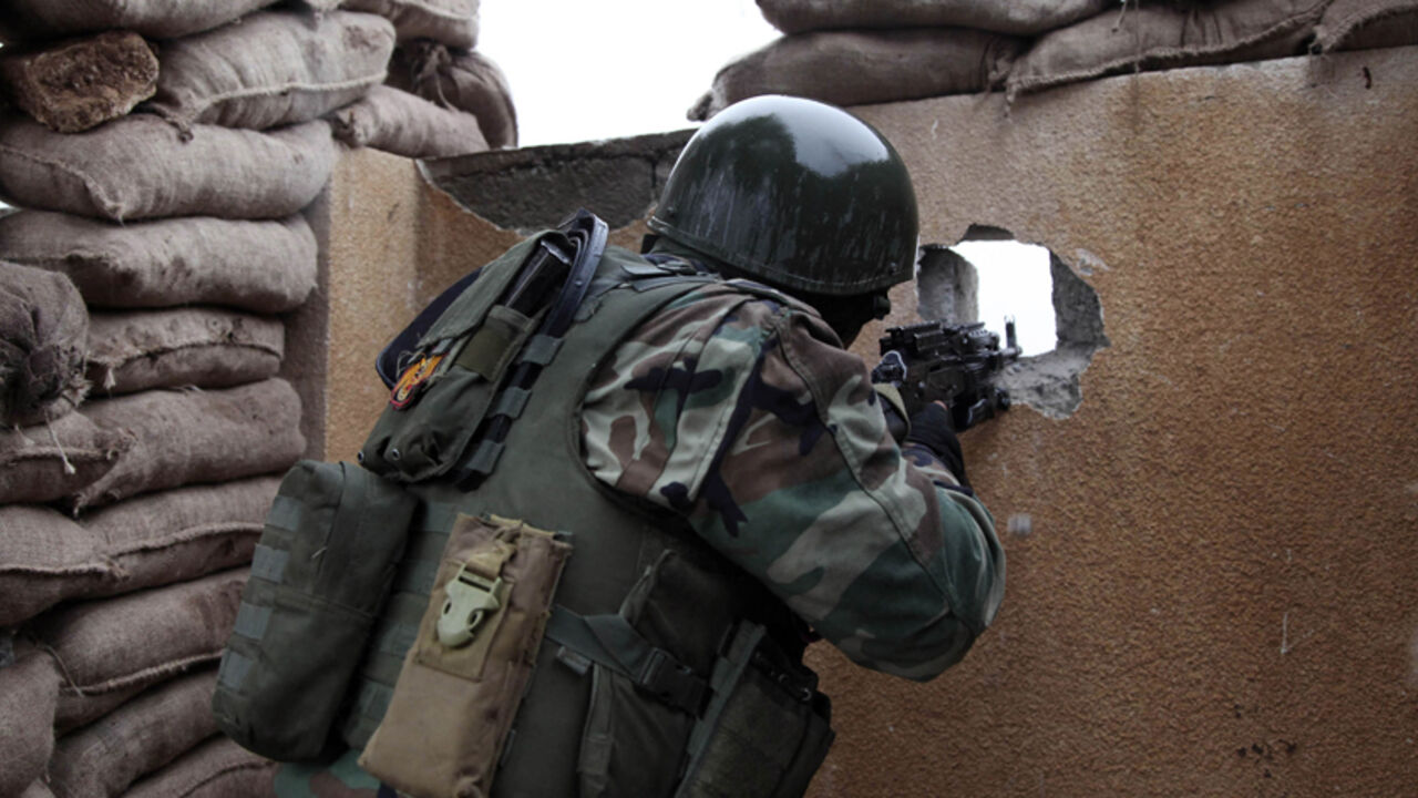 MIDEAST-CRISIS/IRAQ A Kurdish Peshmerga fighter aims his weapon through a hole in a wall on the front line of fighting against Islamic State militants in the outskirts of Mosul January 30, 2015. REUTERS/Ari Jalal (IRAQ - Tags: CIVIL UNREST) - RTR4NNTG