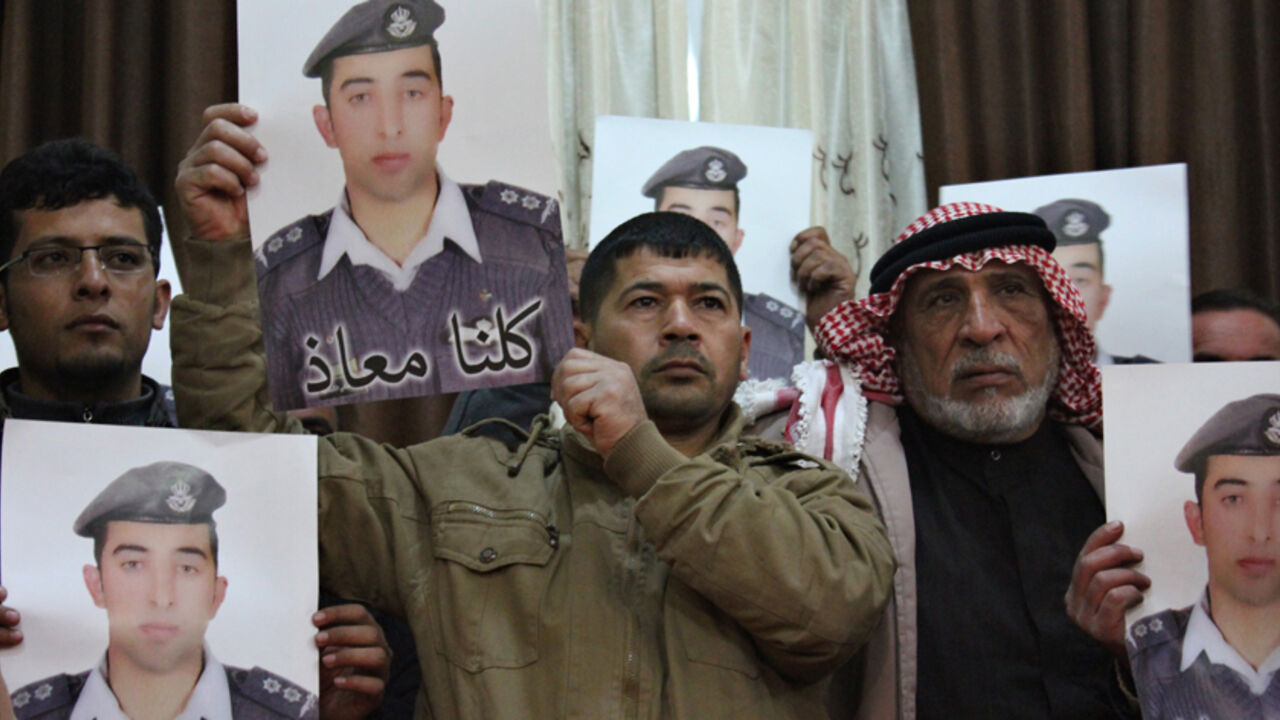 MIDEAST-CRISIS/JAPAN-HOSTAGE Relatives of Islamic State captive Jordanian pilot Muath al-Kasaesbeh hold his poster as they take part in a rally in his support at the family's headquarters in the city of Karak, January 31, 2015. The words on the portrait reads, "We are all Muath." REUTERS/Stringer (JORDAN - Tags: POLITICS CIVIL UNREST TPX IMAGES OF THE DAY) - RTR4NQMF