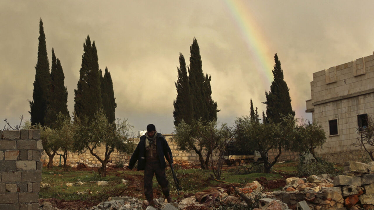 MIDEAST-CRISIS/SYRIA-ALEPPO A rebel fighter carries his weapon as he walks in front of a rainbow in Ratian village, north of Aleppo, after what the rebels said was an offensive against them by forces loyal to Syria's President Bashar al-Assad that attempted to advance in the village but failed to February 18, 2015. Battles in and around the Syrian city of Aleppo have killed at least 70 pro-government fighters and more than 80 insurgents after the army launched an offensive there, a monitoring group said on Wednesday. Picture taken Feb