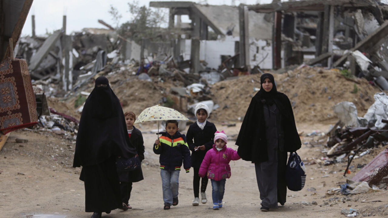 ISRAEL-PALESTINIANS/ Palestinians walk near the ruins of houses that witnesses said were destroyed or damaged by Israeli shelling during a 50-day war last summer, on a winter day east of Gaza City February 20, 2015. REUTERS/Ibraheem Abu Mustafa (GAZA - Tags: POLITICS CIVIL UNREST ENVIRONMENT SOCIETY) - RTR4QE85