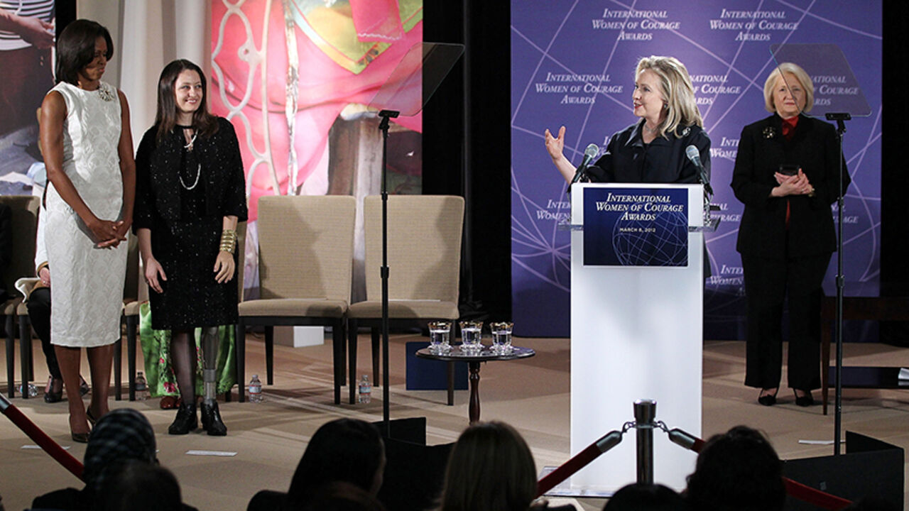 140990510AW008_HILLARY_CLIN WASHINGTON, DC - MARCH 08: Safak Pavey (2nd L), a parliament member of Turkey, is introduced by U.S. Secretary of State Hillary Clinton (2nd R) during a presentation ceremony of the International Women of Courage Awards as first lady Michelle Obama (L) looks on at the State Department March 8, 2012 in Washington, DC. Ten women from around the world were presented with the awards during the sixth annual ceremony to recognize their courage and leadership. (Photo by Alex Wong/Getty Images)