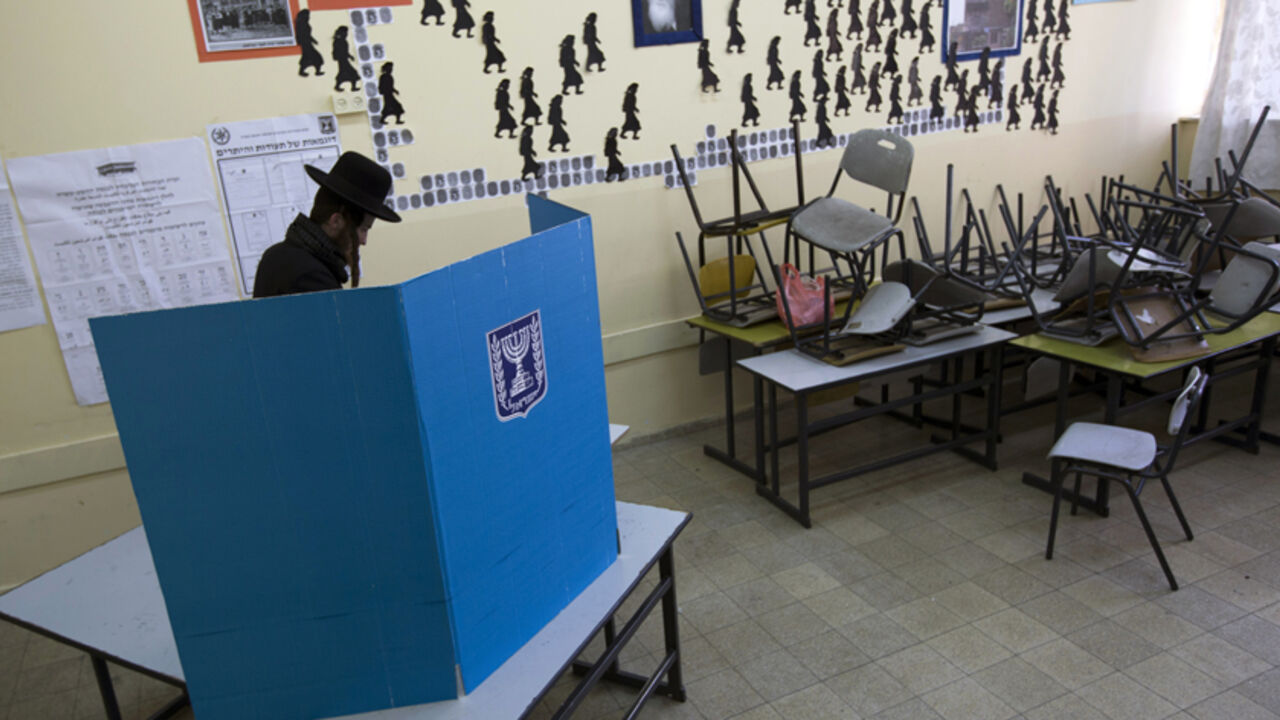 ISRAEL-ELECTION/VOTING An ultra-Orthodox Jewish man stands behind a booth as he votes in the parliamentary election at a polling station in Jerusalem January 22, 2013. Israelis voted on Tuesday in an election that is expected to see Prime Minister Benjamin Netanyahu win a third term in office, pushing the Jewish state further to the right, away from peace with the Palestinians and towards a showdown with Iran. REUTERS/Ronen Zvulun (JERUSALEM - Tags: POLITICS ELECTIONS) - RTR3CSDF