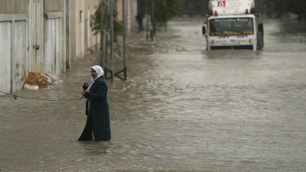 A Palestinian journalist speaks to the camera as she stands on a flooded street following heavy rain in Gaza City November 27, 2014. The civil defence asked residents in an area east of Gaza City to evacuate their homes to avoid being trapped in flood waters from a nearby lake. REUTERS/Mohammed Salem (GAZA - Tags: SOCIETY ENVIRONMENT MEDIA TPX IMAGES OF THE DAY) - RTR4FST8