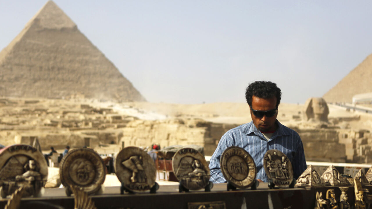 EGYPT-TOURISM/ A souvenirs vendor waits for tourists in front of the Sphinx and the Giza Pyramids on the outskirts of Cairo, December 9, 2014. Egypt's tourism revenues jumped 112 percent to about $2 billion in the third quarter of 2014, a tourism ministry official said, suggesting the key industry was showing signs of recovery, albeit from a particularly bad third quarter last year. Tourism, an important source of foreign currency, has been hammered since the popular uprising that toppled Hosni Mubarak in 2011. REUTERS