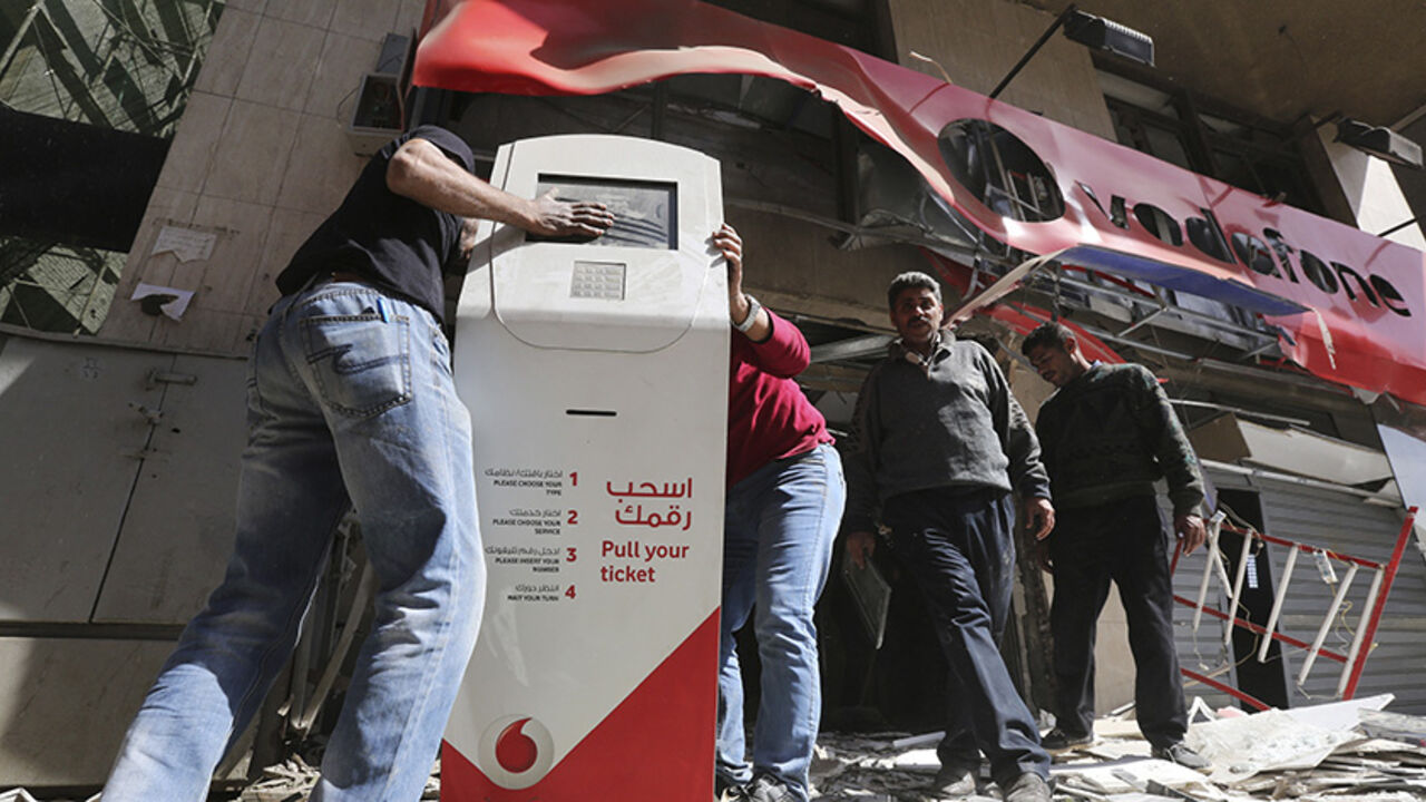 EGYPT-VIOLENCE/ Workers clear debris outside a Vodafone branch following a blast, in Cairo February 26, 2015. One person was killed and five others wounded when five bombs exploded in different locations around Cairo on Thursday, security sources said. REUTERS/Mohamed Abd El Ghany (EGYPT - Tags: CIVIL UNREST BUSINESS TELECOMS) - RTR4R9L2