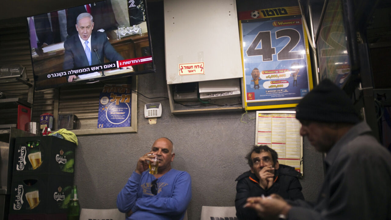 USA-ISRAEL/ People sit under a television broadcasting Israel's Prime Minister Benjamin Netanyahu's speech to the U.S. Congress, at a kiosk in the southern city of Ashkelon March 3, 2015. Netanyahu warned U.S. President Barack Obama on Tuesday against accepting a nuclear deal with Iran that would be a "countdown to a potential nuclear nightmare" by a country that "will always be an enemy of America". REUTERS/Amir Cohen (ISRAEL - Tags: POLITICS) - RTR4RWZN