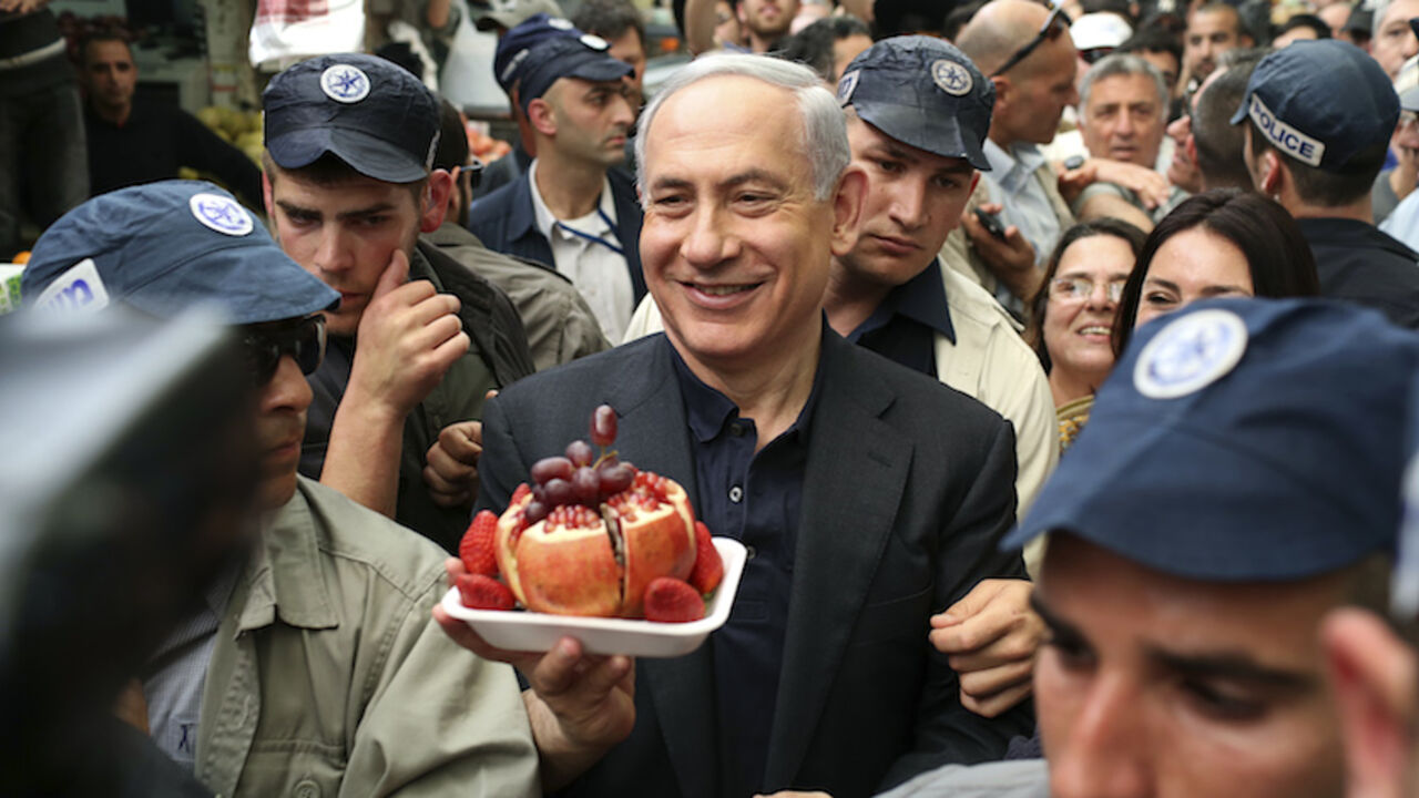 Israel's Prime Minister Netanyahu holds a plate of fruit in Jerusalem Israel's Prime Minister Benjamin Netanyahu (C) holds a plate of fruit during a visit to Mahane Yehuda fruit and vegetable market in Jerusalem March 9, 2015. Israelis will vote in a parliamentary election on March 17, choosing among party lists of candidates to serve in the 120-seat Knesset. Currently, polls show Netanyahu's Likud party and the centre-left Zionist Union opposition running neck-and-neck, with each predicted to win around 24 seats in the Knesset. REUTERS/Noam Moskowitz (JERUSALEM - Tags: POLIT