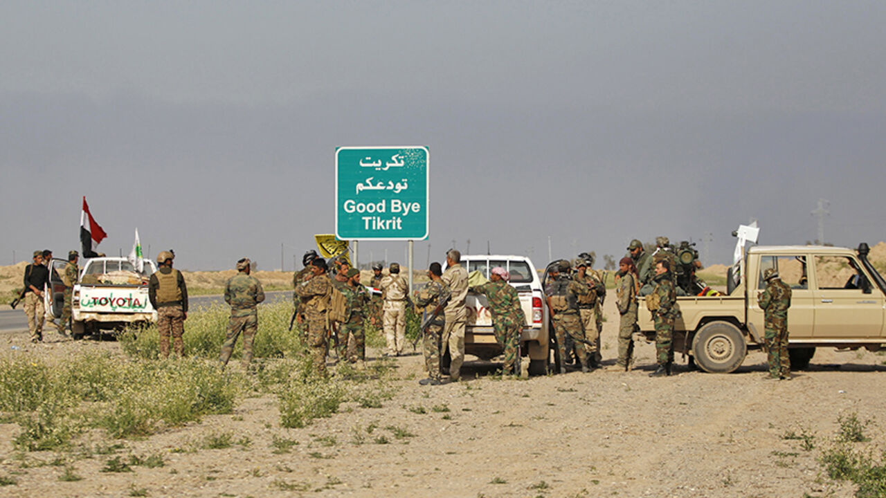 MIDEAST-CRISIS-IRAQ-KIRKUK Shi'ite fighters gather with their weapons next to a sign in the town of al-Alam March 9, 2015. Just north of Tikrit, home city of executed Sunni former president Saddam Hussein, Iraqi security forces and Shi?ite militia fighters began an offensive against Islamic State to regain control over the town of al-Alam. REUTERS/Thaier Al-Sudani (IRAQ - Tags: POLITICS CIVIL UNREST CONFLICT) - RTR4SOF4
