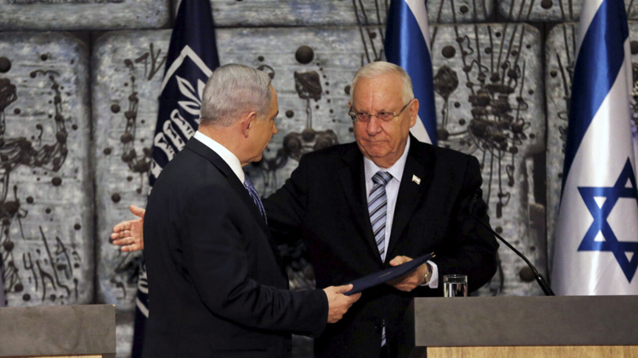 ISRAEL-NETANYAHU/GOVERNMENT Israeli Prime Minister Benjamin Netanyahu (L) receives a folder from Israeli President Reuven Rivlin during a ceremony in Jerusalem March 25, 2015. Netanyahu, grappling with fierce White House disapproval, won consent from Israel's president on Wednesday to try to form a new coalition government. REUTERS/Ammar Awad - RTR4UVGJ