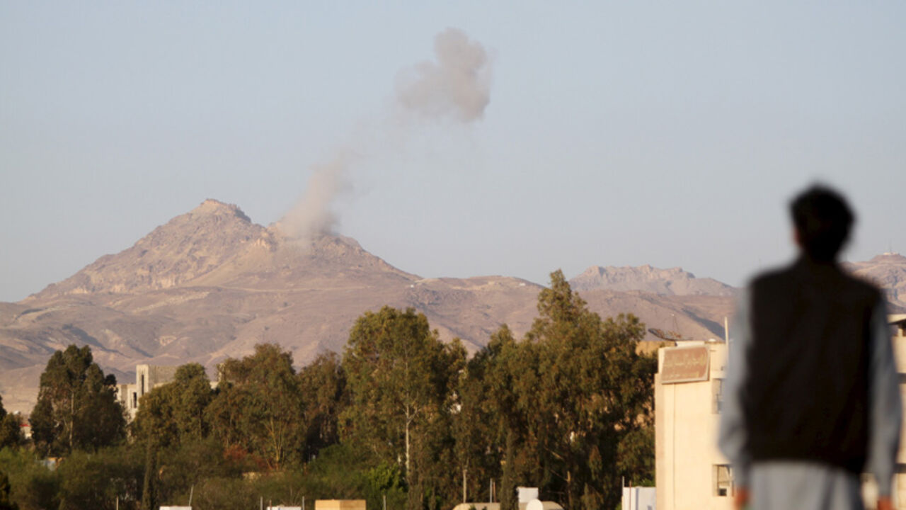 YEMEN-SECURITY/ A man looks on as smoke billows from military barracks in the Jabal al-Jumaima mountain following an air strike near Sanaa March 30, 2015. REUTERS/Mohamed al-Sayaghi - RTR4VHP4