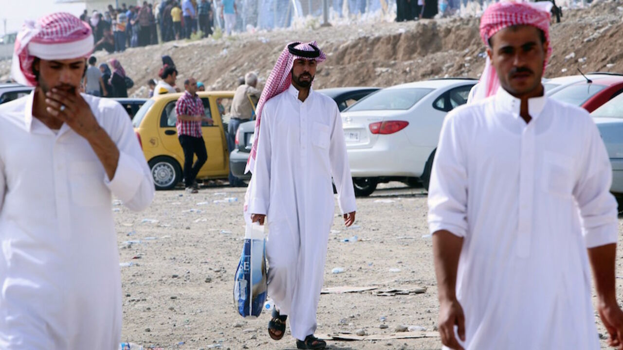 Nic6337663 Tribesmen walk at a temporary camp set up to shelter Iraqis fleeing violence in Iraq's northern Nineveh province on June 12, 2014, in Aski kalak, 40 kms West of Arbil, in the autonomous Kurdistan region. Thousands of people who fled Iraq's second city of Mosul after it was overrun by jihadists wait in the blistering heat, hoping to enter the safety of the nearby Kurdish region and furious at Baghdad's failure to help them. many as half a million people are thought to have fled Mosul, which was captured by