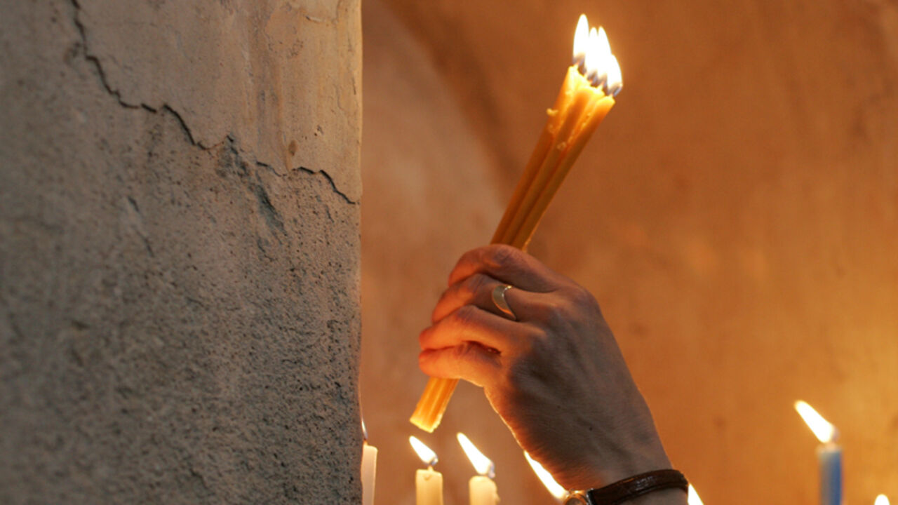 A woman places lit candles in the renovated Armenian church, perched on Akdamar Island in Lake Van, near the eastern Turkish city of Van, March 29, 2007. Turkey spent USD1,5 million in the restoration of the ancient Akdamar church, one of the most precious remnants of Armenian culture that will be converted in a museum. REUTERS/Umit Bektas (TURKEY) - RTR1O2EW