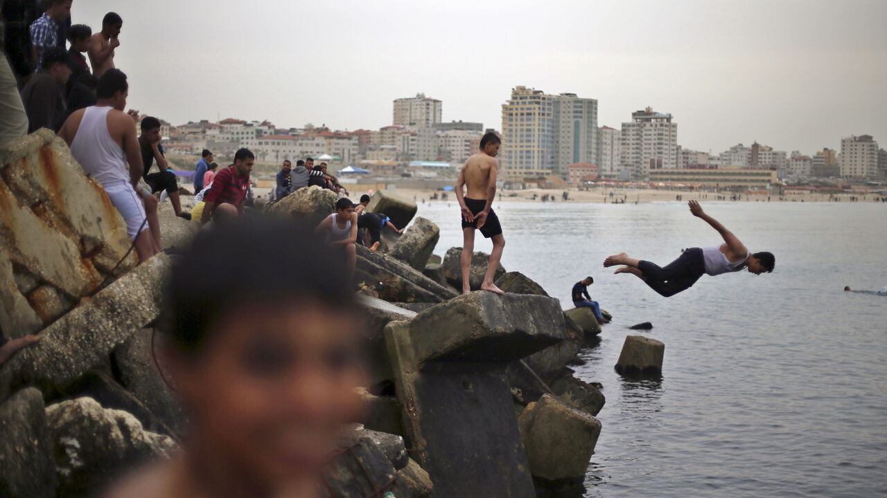 A Palestinian boy jumps into the Mediterranean Sea as he enjoys a warm day with others at the seaport of Gaza City March 27, 2015. REUTERS/Mohammed Salem 







